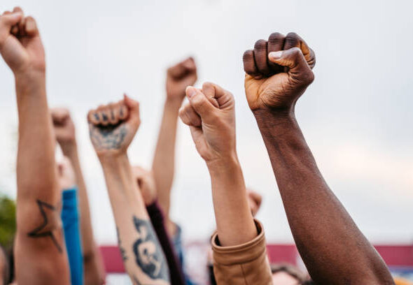 Close-up of protestors raising hands above their heads.